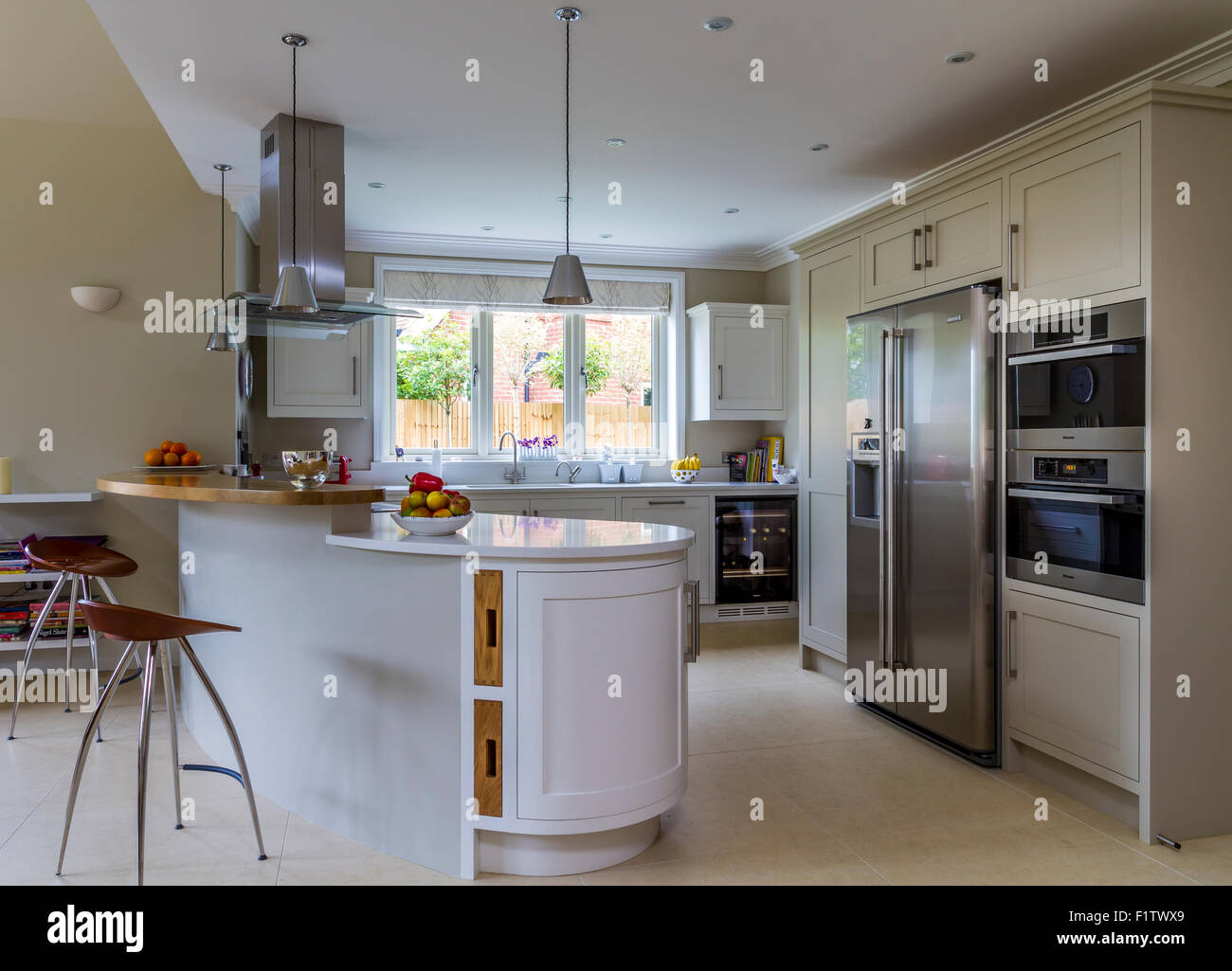 White painted kitchen with ovens, American style FridgeFreezer and large peninsular unit Stock Photo