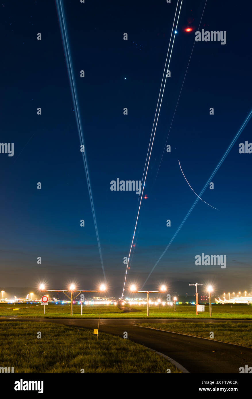 Traces from landing airplanes are illuminating the dark sky above the touch-down point of runway 28 of Zurich Kloten airport. Stock Photo