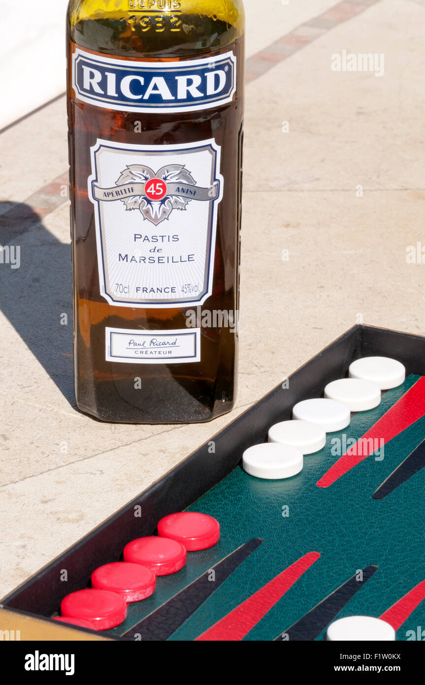 A bottle of Ricard on a French cafe table next to a backgammon board. Stock Photo