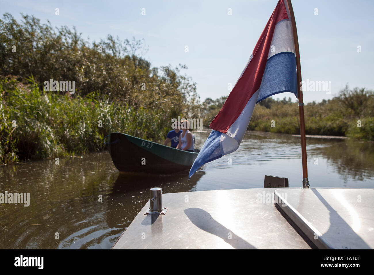 Tourists sailing a rent boat with Dutch flag at National Park 'de Biesbosch' on a sunny day in the Netherlands Stock Photo