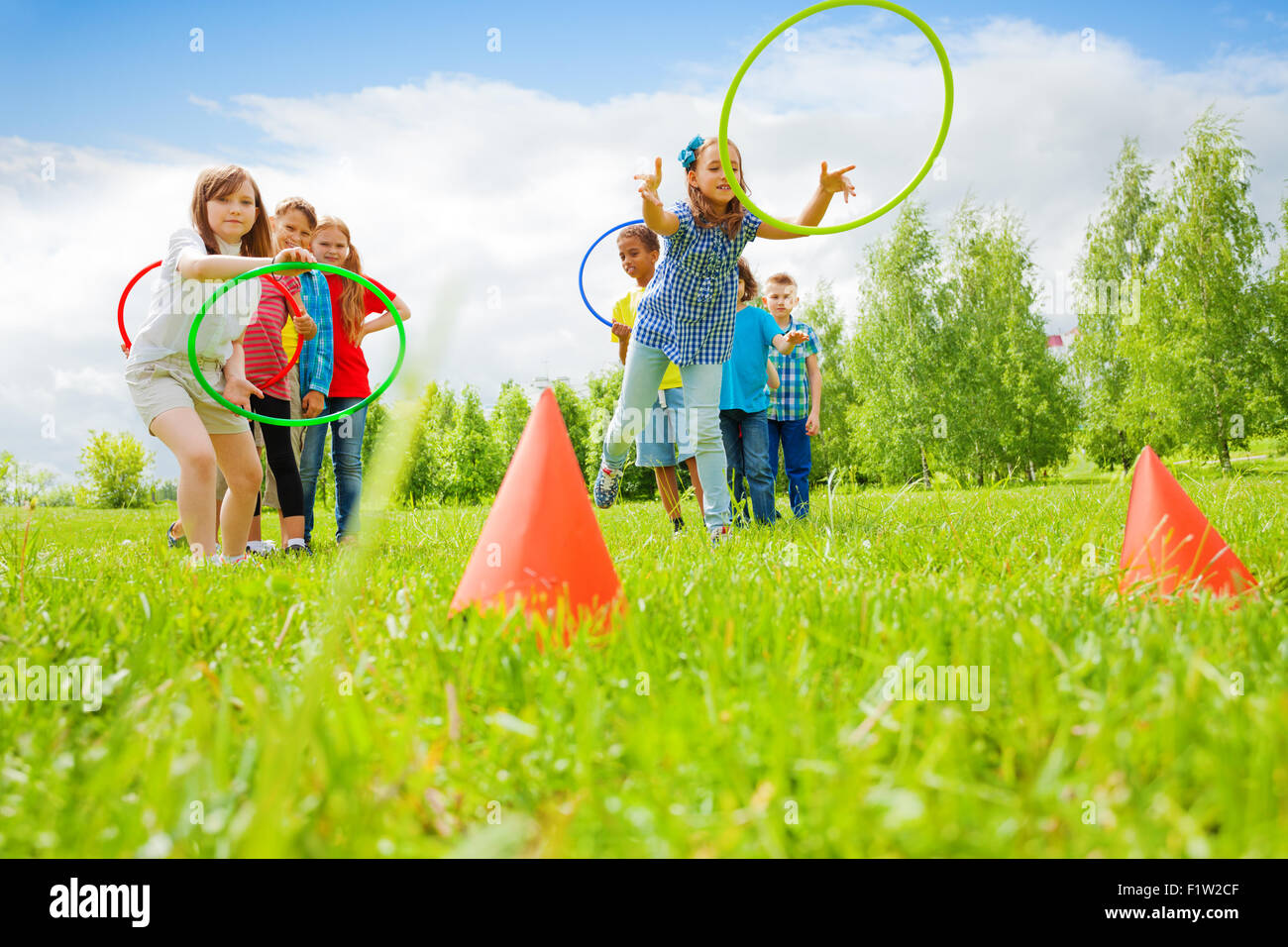 Kids playing and throwing colorful hoops on cones Stock Photo Alamy