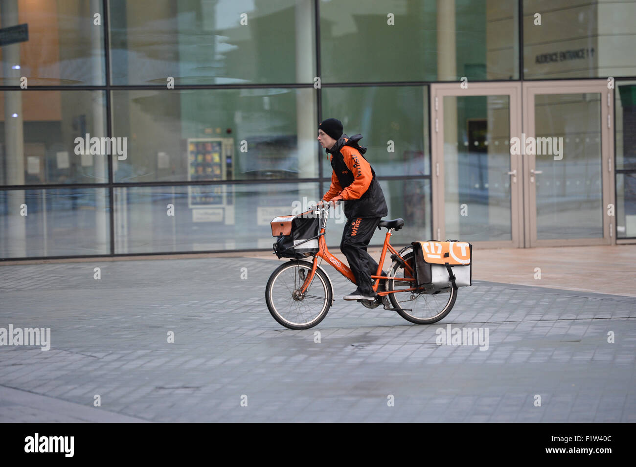 A TNT postman delivers mail to an address in Media City Manchester. Stock Photo
