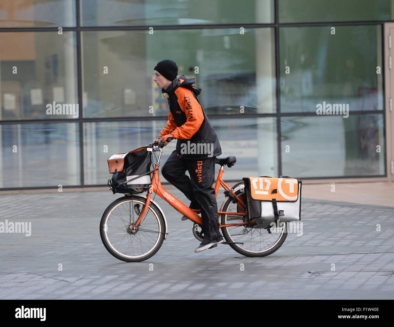 A TNT postman delivers mail to an address in Media City Manchester. Stock Photo