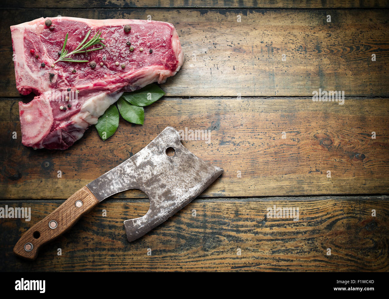 Raw beef steak with spices and meat hatchet on a wooden board. Stock Photo