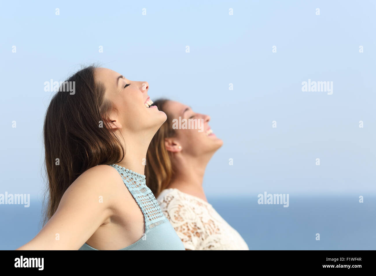 Two girls doing breath exercises inhaling fresh air on the beach Stock Photo