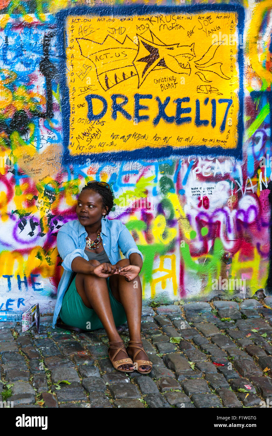 Young woman tourist sitting beside the John Lennon Wall, Prague, Czech Republic. Stock Photo