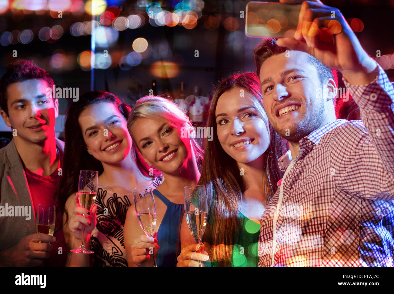 friends taking selfie by smartphone in night club Stock Photo