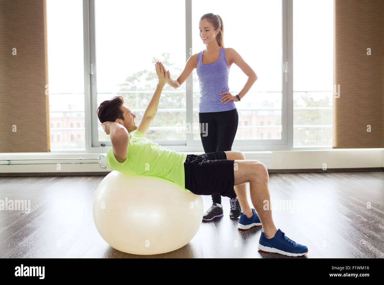 smiling man and woman with exercise ball in gym Stock Photo - Alamy