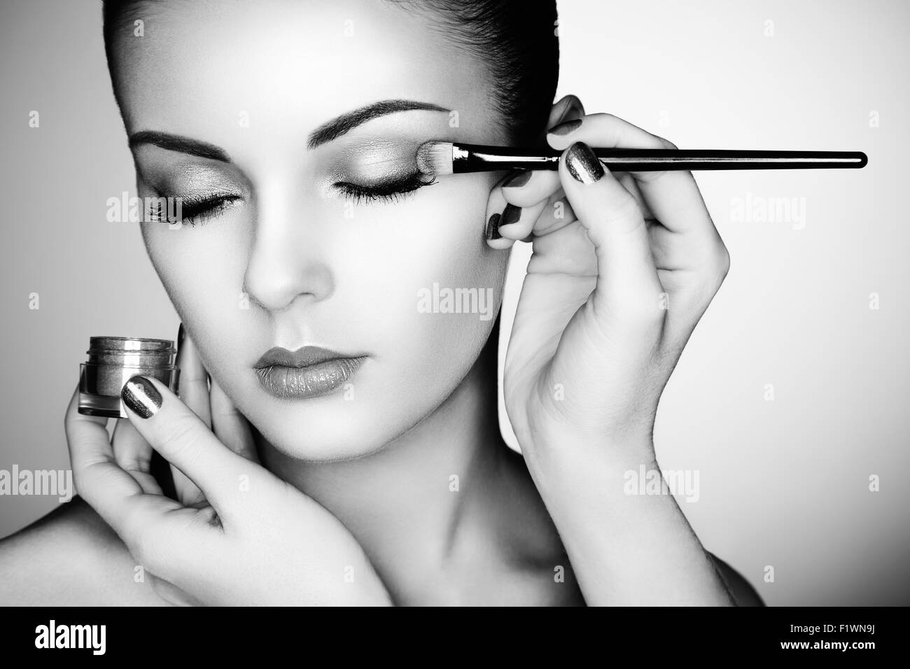 Makeup artist applies eye shadow. Beautiful woman face. Perfect makeup. Black and white Stock Photo