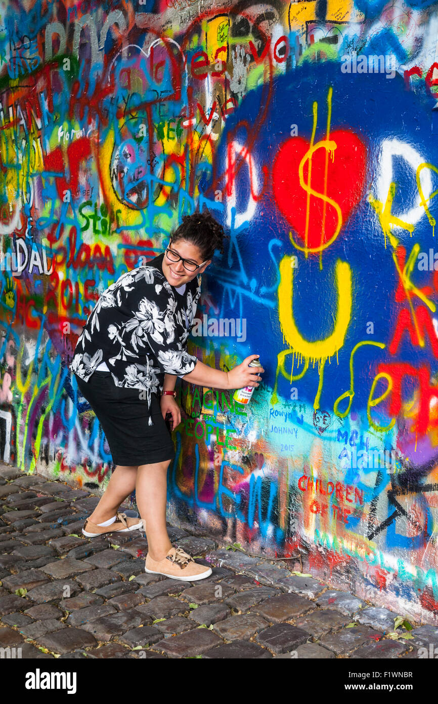 Tourist adding to the graffiti on the John Lennon Wall, Velkoprevorske namesti, Mala Strana, Prague, Czech Republic Stock Photo