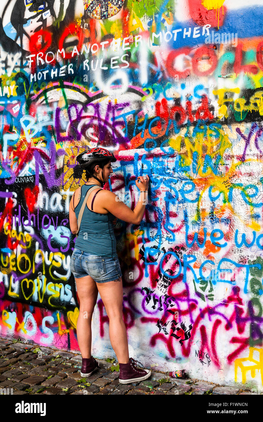 Tourist adding to the graffiti on the John Lennon Wall, Velkoprevorske namesti, Mala Strana, Prague, Czech Republic Stock Photo