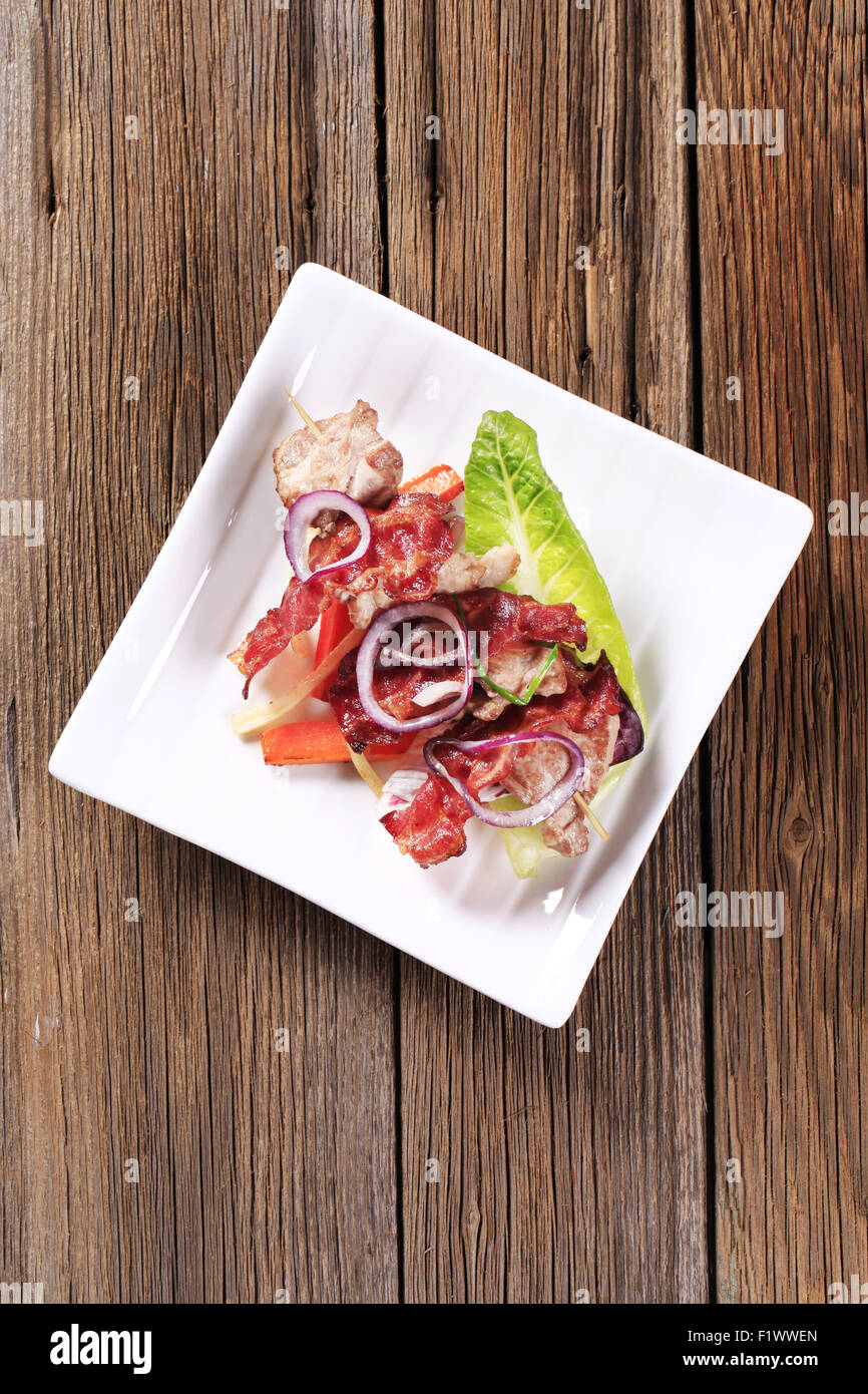 Meat skewer with crispy rashers of bacon and vegetables Stock Photo