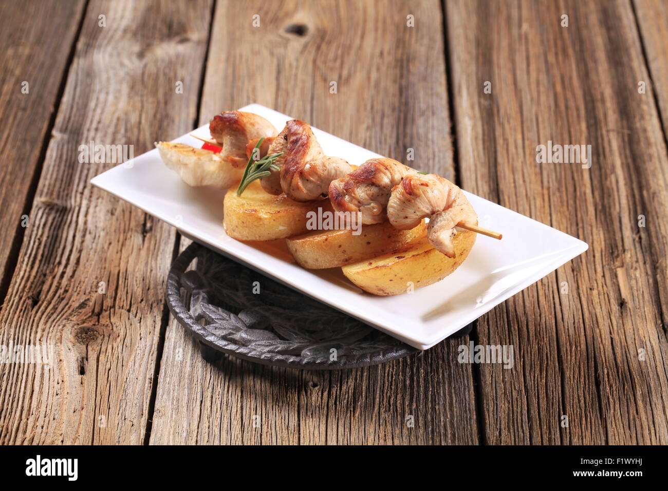 Chicken souvlaki on slices of roasted potato Stock Photo