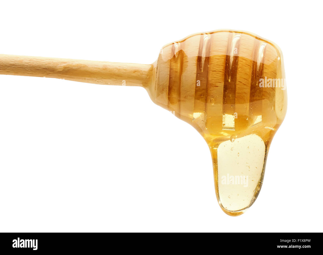 Honey dripping from a wooden honey dipper isolated on the white background. Stock Photo