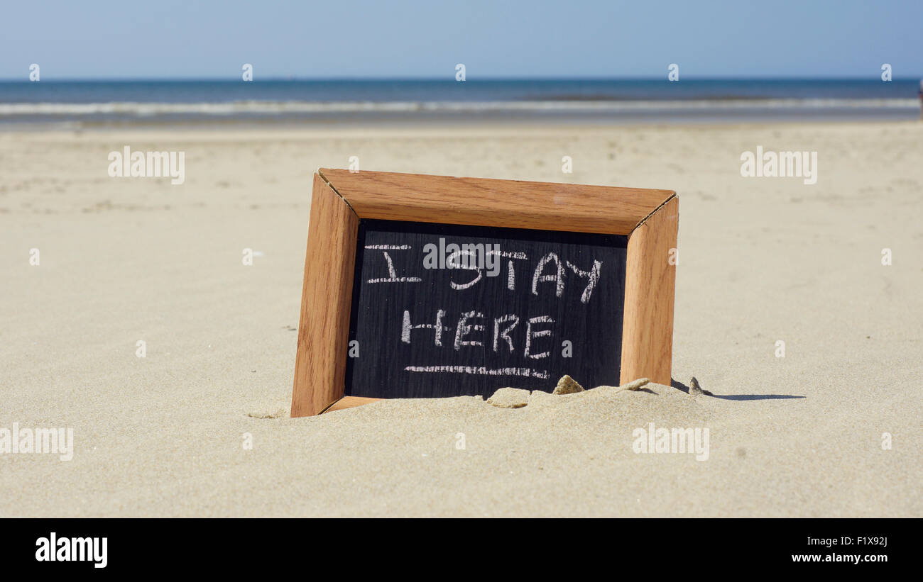 I stay here written on a chalkboard at the beach Stock Photo - Alamy