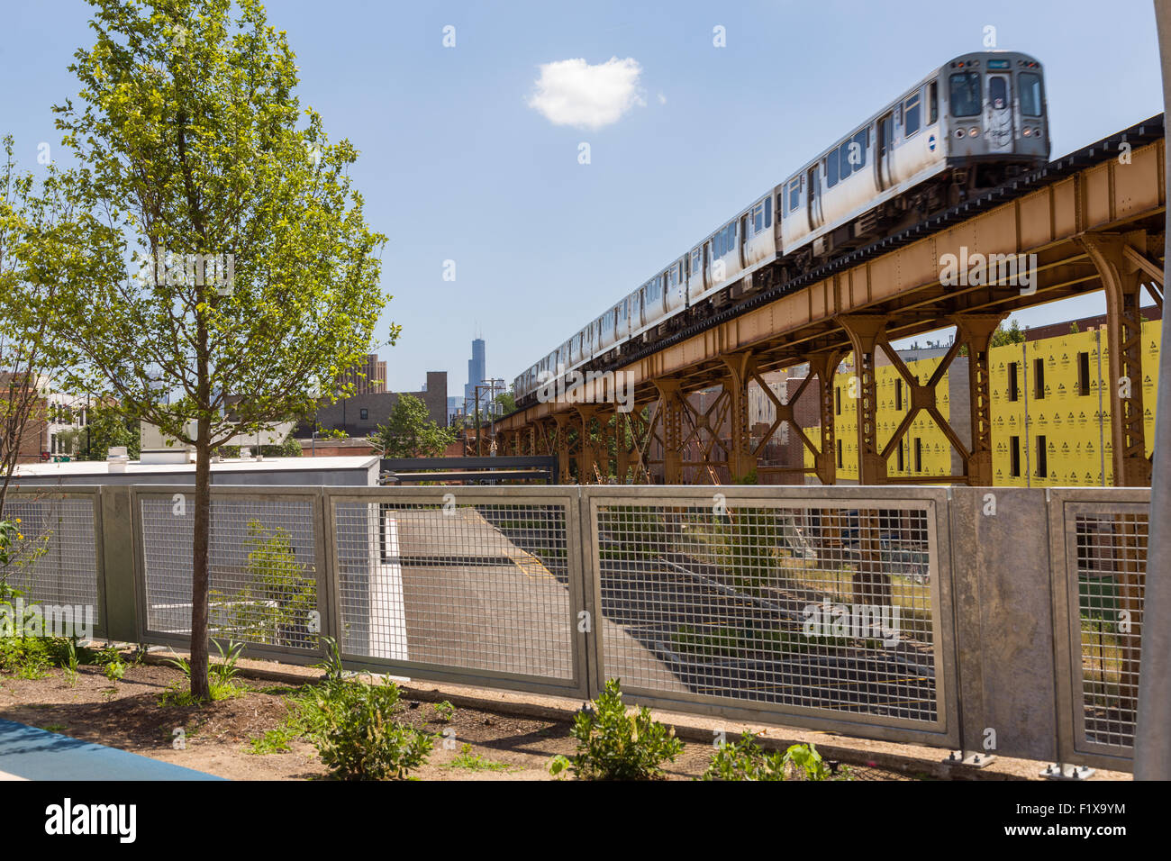An L train on the Blue Line overpass at Milwaukee Avenue along the 606 elevated bike trail, green space and park built on the old Bloomingdale Line in the Wicker Park neighborhood in Chicago, Illinois, USA Stock Photo