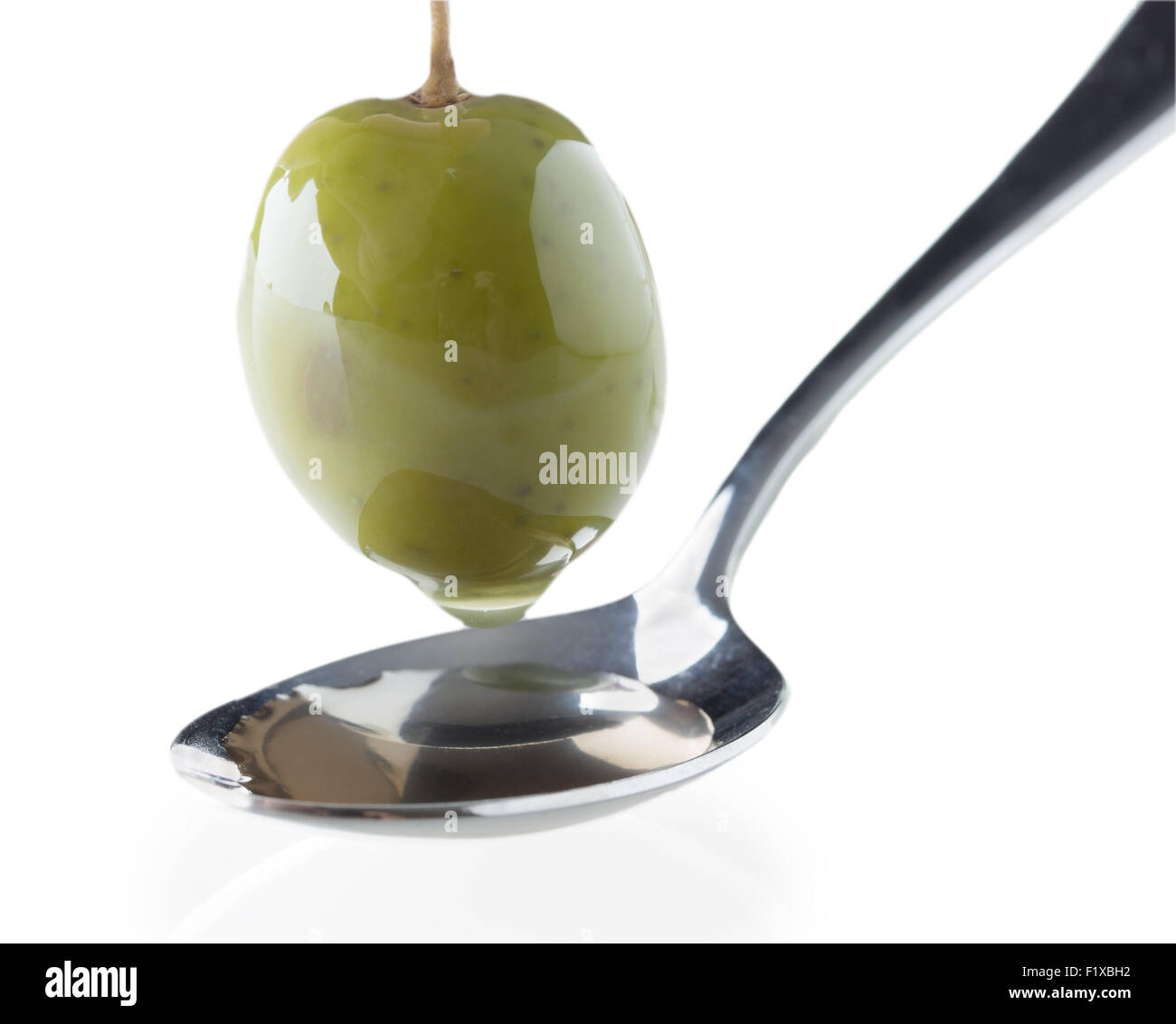 ripe green olive on a spoon on white background Stock Photo
