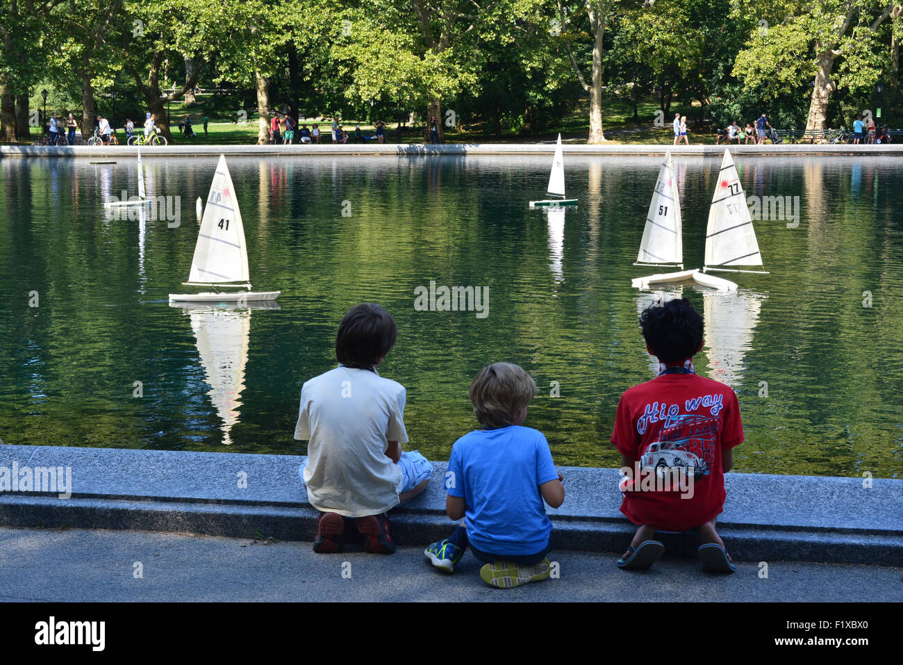 Kids sailing model boats on Water Conservatory in Central Park in New York City. Stock Photo