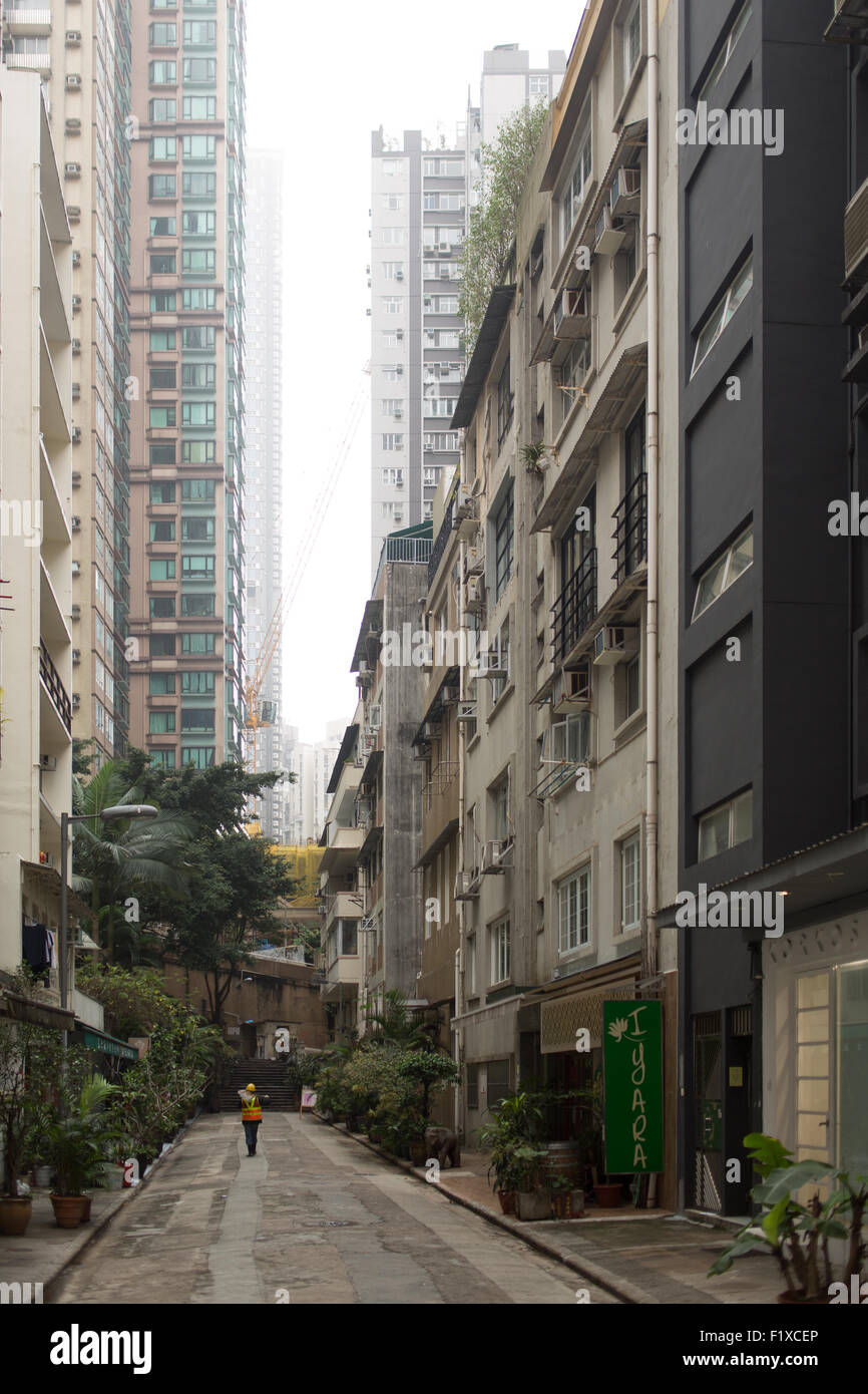 Road worker walking between high rise apartments in Hong Kong's Mid