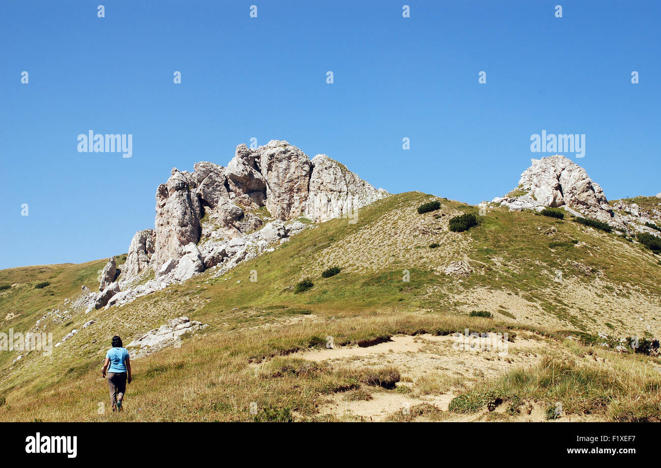 A female trekker walks towards a high point  at the top of the Jelenak pass on the Albanian Montenegro boarder Stock Photo