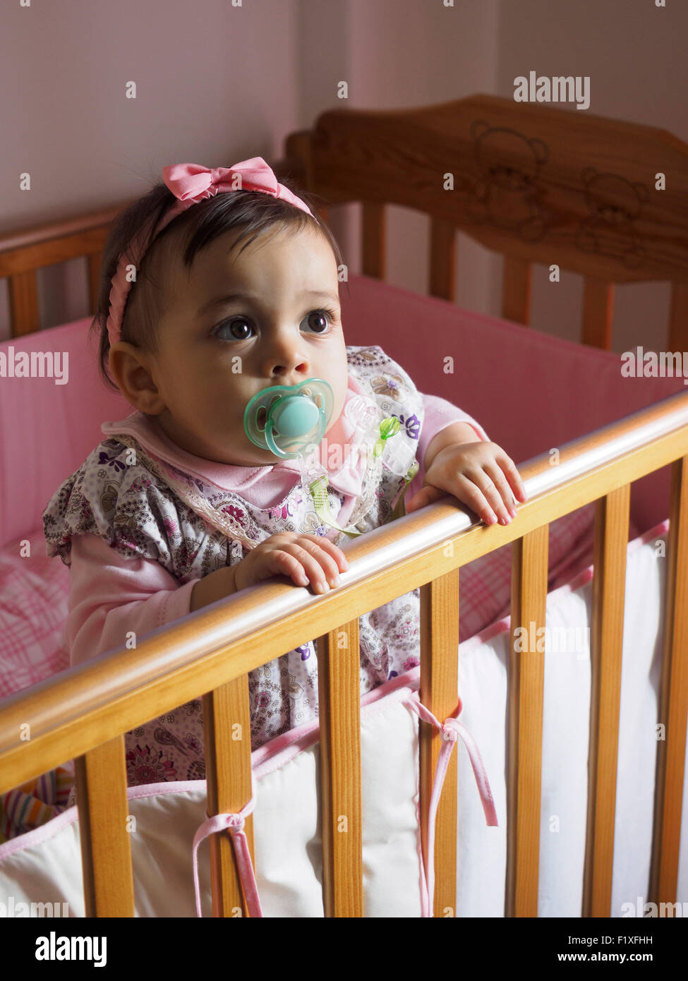 Baby girl with pacifier inside crib Stock Photo