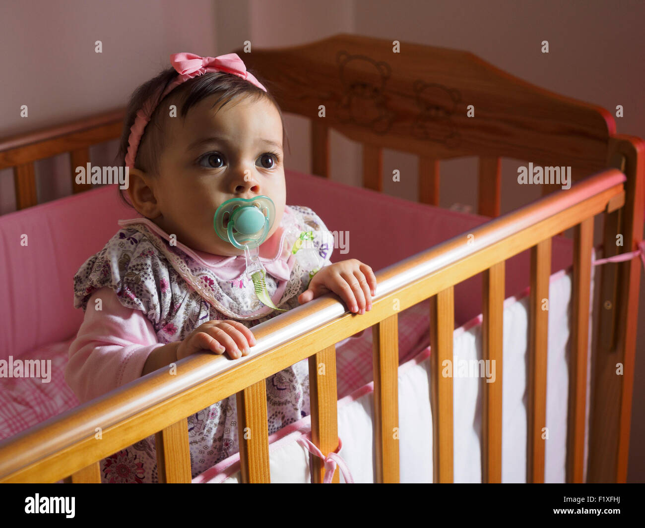 Baby girl with pacifier inside crib Stock Photo