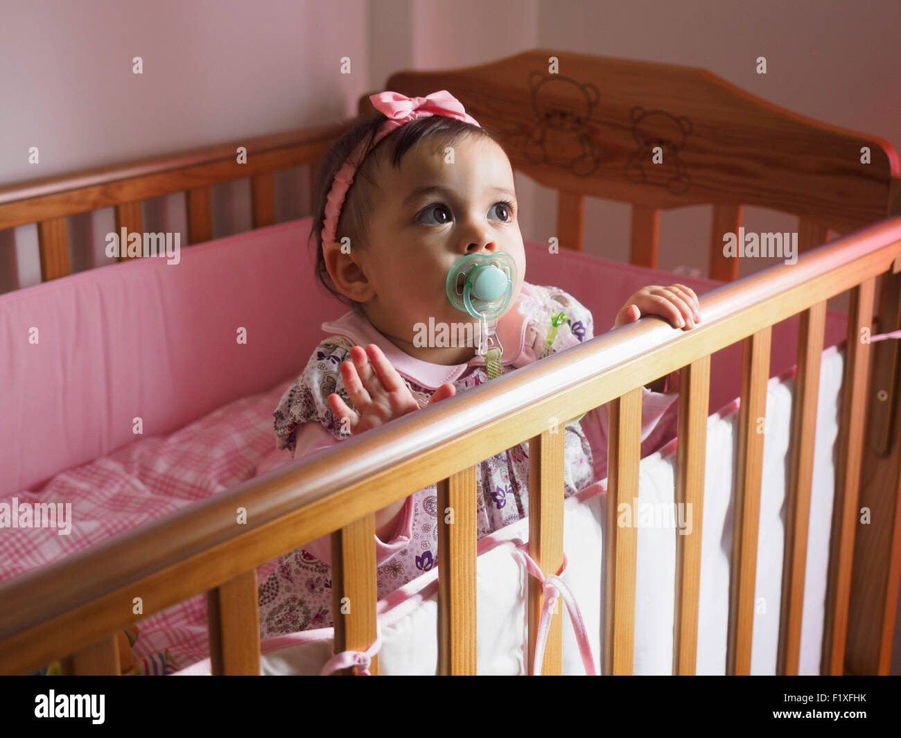 Baby girl with pacifier inside crib Stock Photo