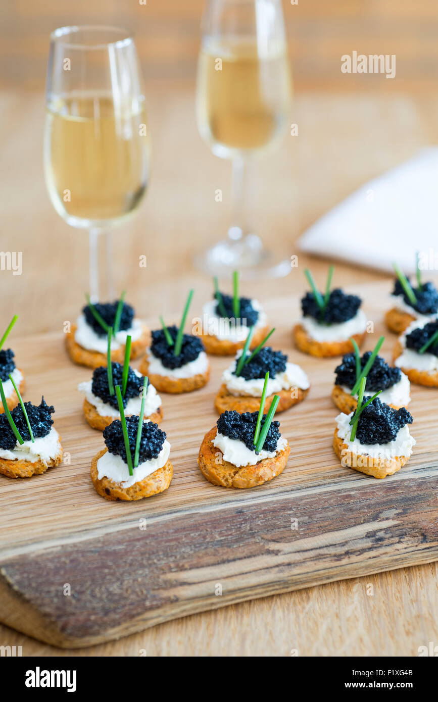 Canapes made from crostini with soft cheese and seaweed 'caviar'. Stock Photo