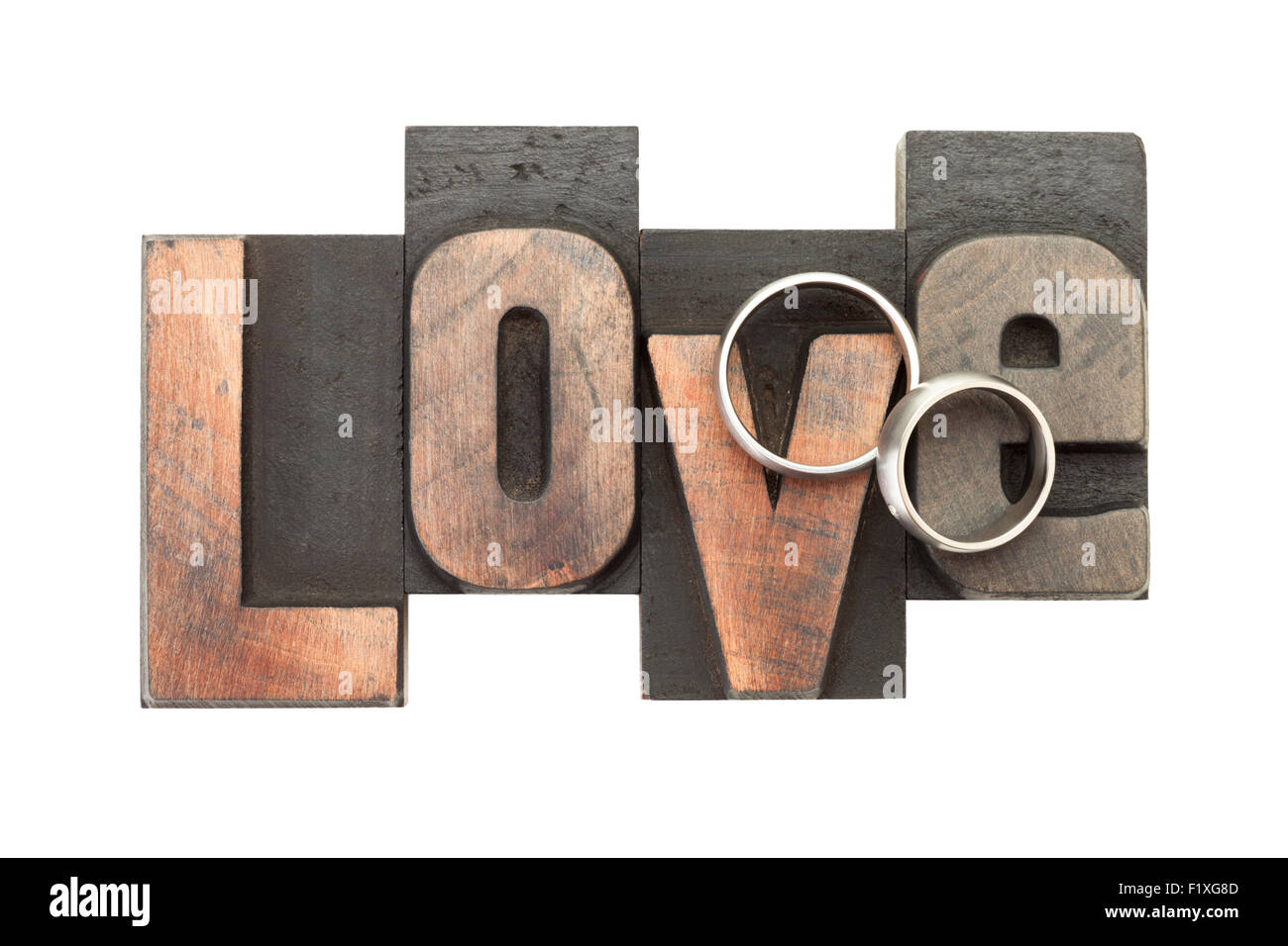 wedding rings upon the word love, written with vintage letterpress printing blocks, isolated on white background Stock Photo