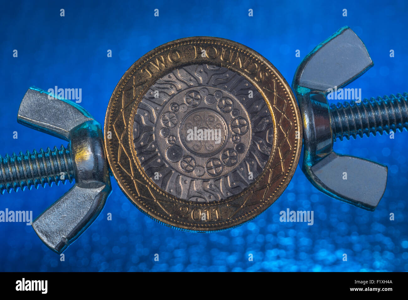 Turn the screw concept, pressurize, press. Macro of UK £2 coin being