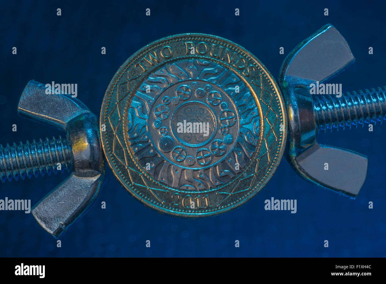 Turn the screw concept, pressurize, press. Macro of UK £2 coin being