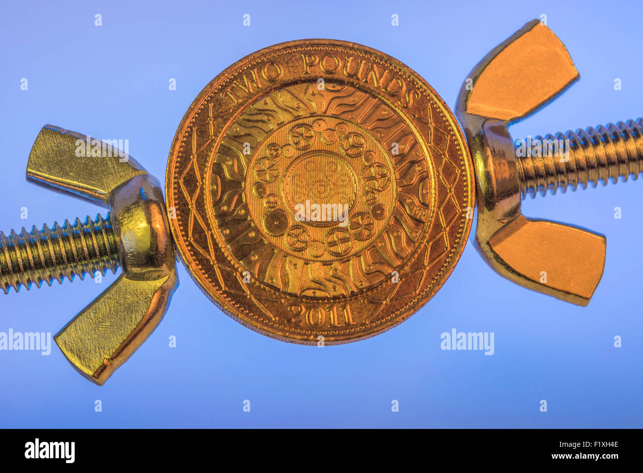 Turn the screw concept, pressurize, press. Macro of UK £2 coin being