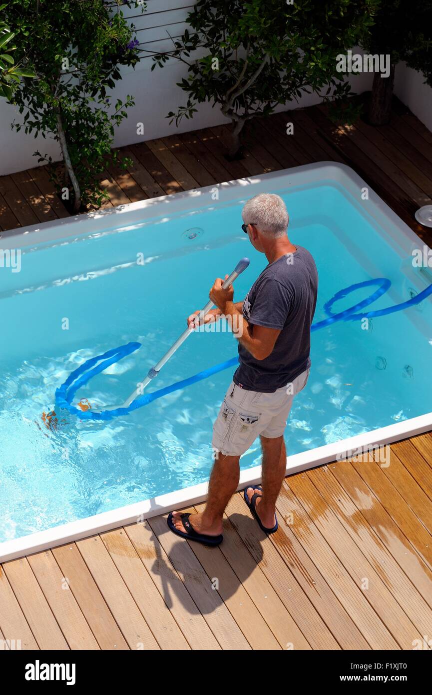 A man vacuuming a plunge pool in a holiday complex Santorini Greece Stock Photo