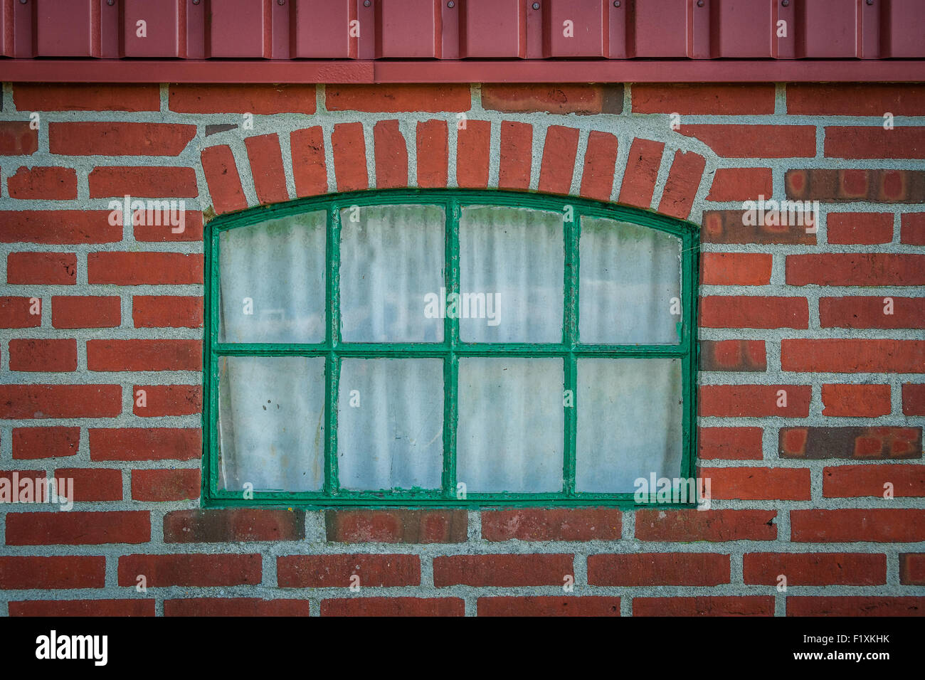 Green window on a house made of red bricks Stock Photo