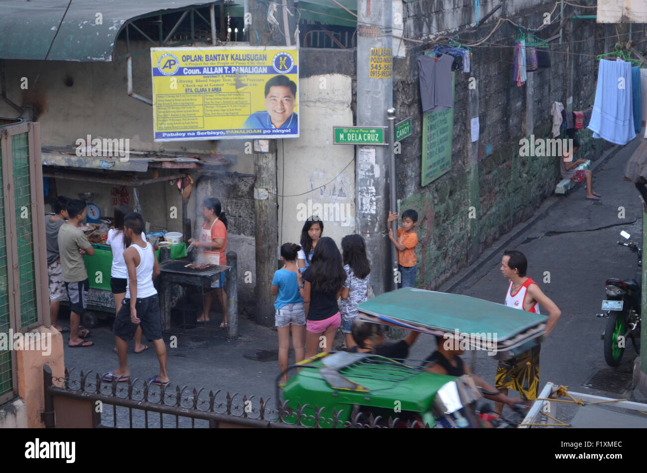 M.Dela Cruz, Manila. A street corner where crowds gather to taste fresh adobo, or fresh chicken,orsausagesbeing warmedup forthem Stock Photo