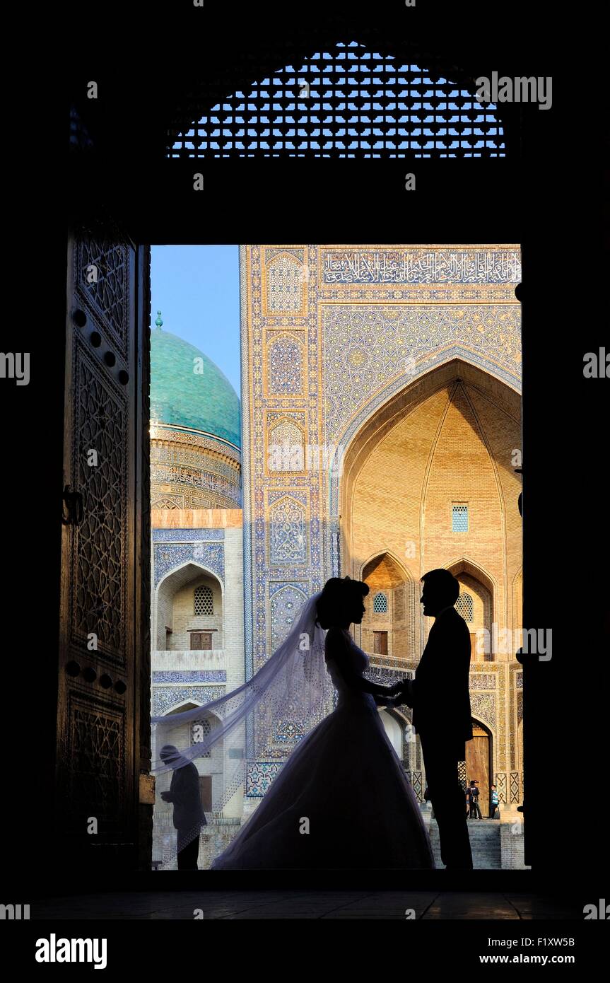 Uzbekistan, Bukhara, historic centre listed as World Heritage by UNESCO, wedding photography, silhouettes of bride and groom in front of the Mir-i-Arab Madrasa Stock Photo