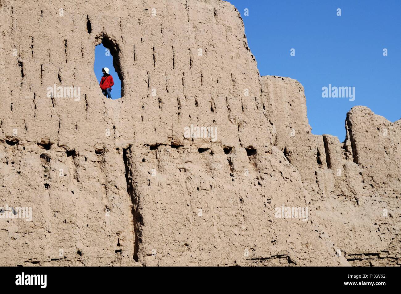 Uzbekistan, Karakalpakstan, woman in a hole in a wall of Qyzyl Qala desert fortress Stock Photo