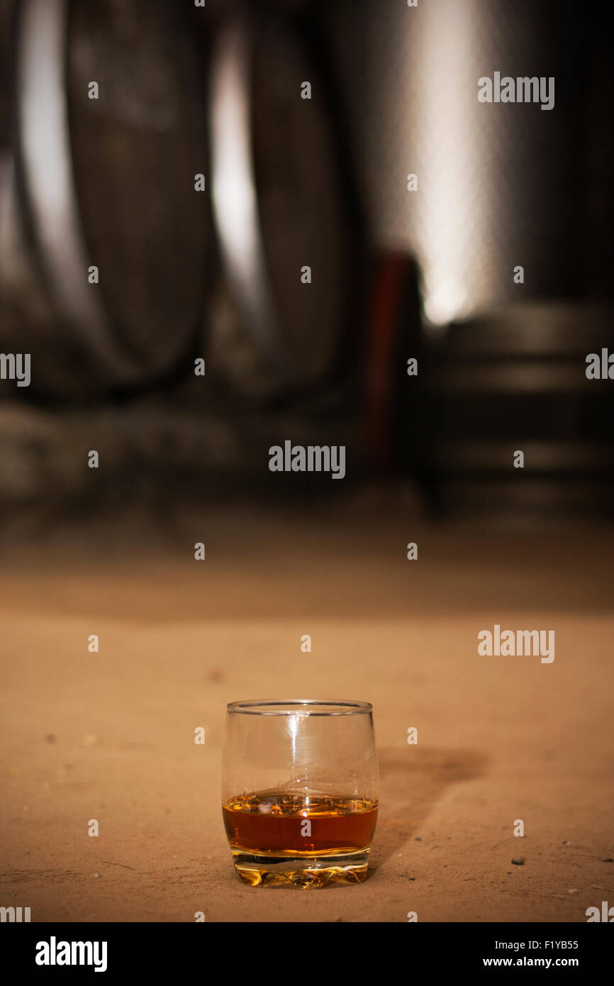 Glass filled with whiskey, neat without ice, standing on floor in