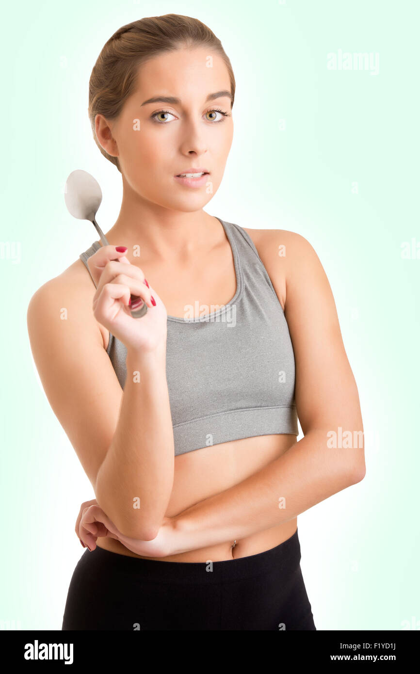 Fit sporty woman holding a spoon isolated in green Stock Photo