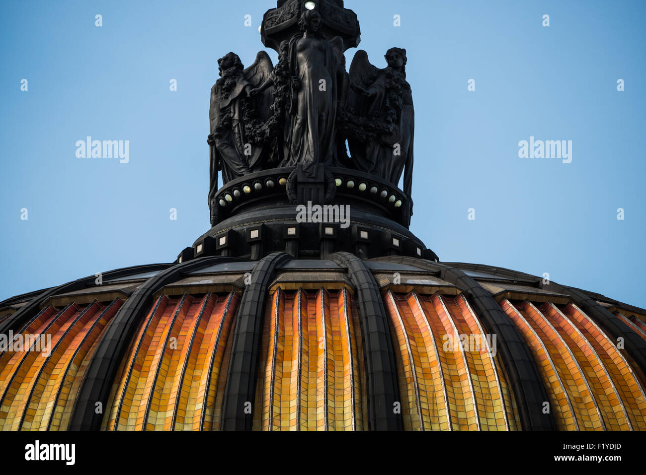 Palacio De Bellas Artes Dome Sculptures Mexico City // MEXICO CITY, Mexico — Sculptural figures adorning the main dome of the Palacio de Bellas Artes showcase Mexico's national symbol, an eagle, crowning a series of statues representing the dramatic arts. This early 20th-century masterpiece, housing Mexico's National Theater, combines Neo Classical and Art Nouveau exterior elements with an Art Deco interior. The building stands as a cornerstone of Mexico City's UNESCO World Heritage designated Centro Histórico district. Stock Photo