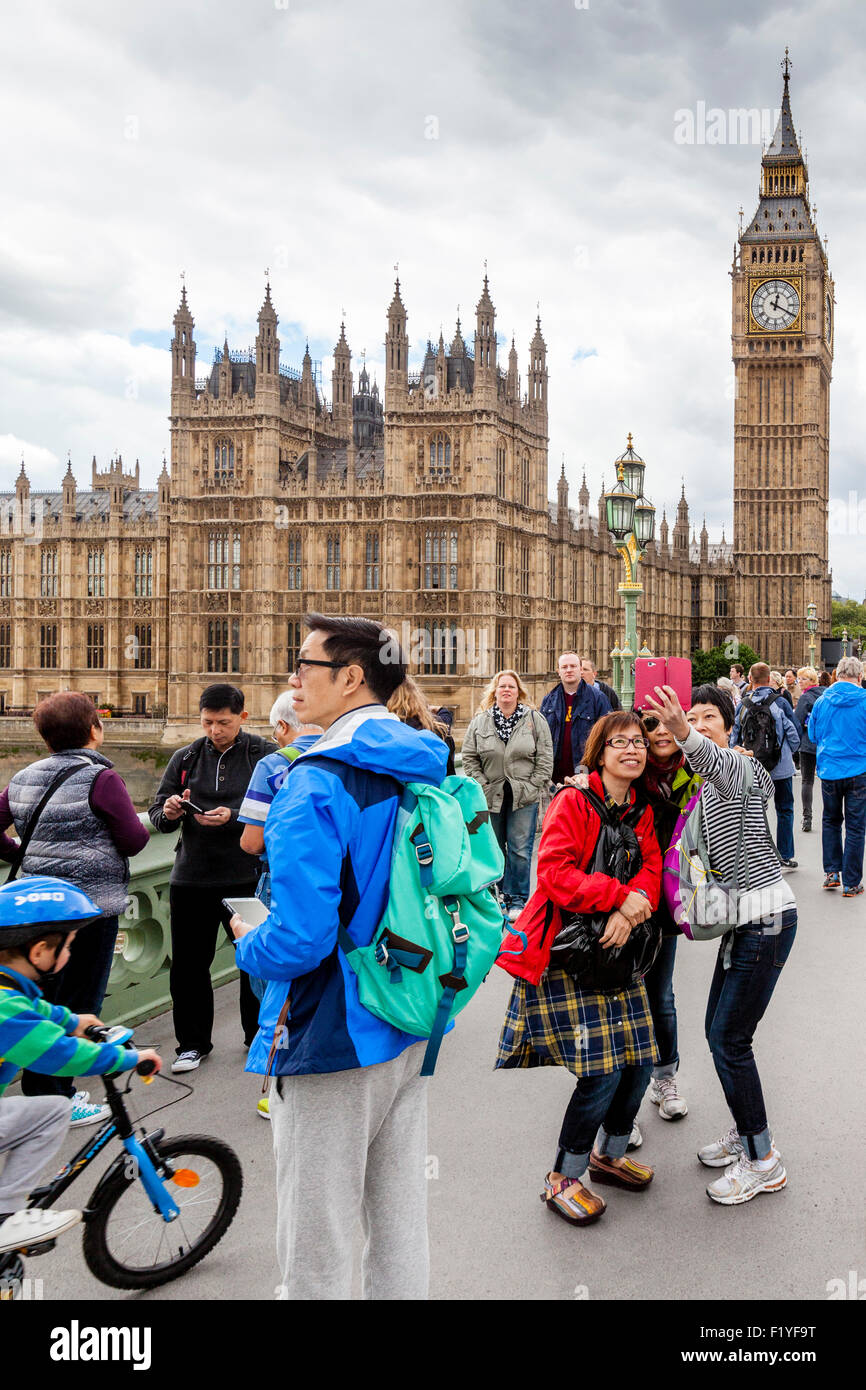 Young Tourists Pose For Selfies In Front Of Big Ben and The Houses Of Parliament, Westminster Bridge, London, England Stock Photo