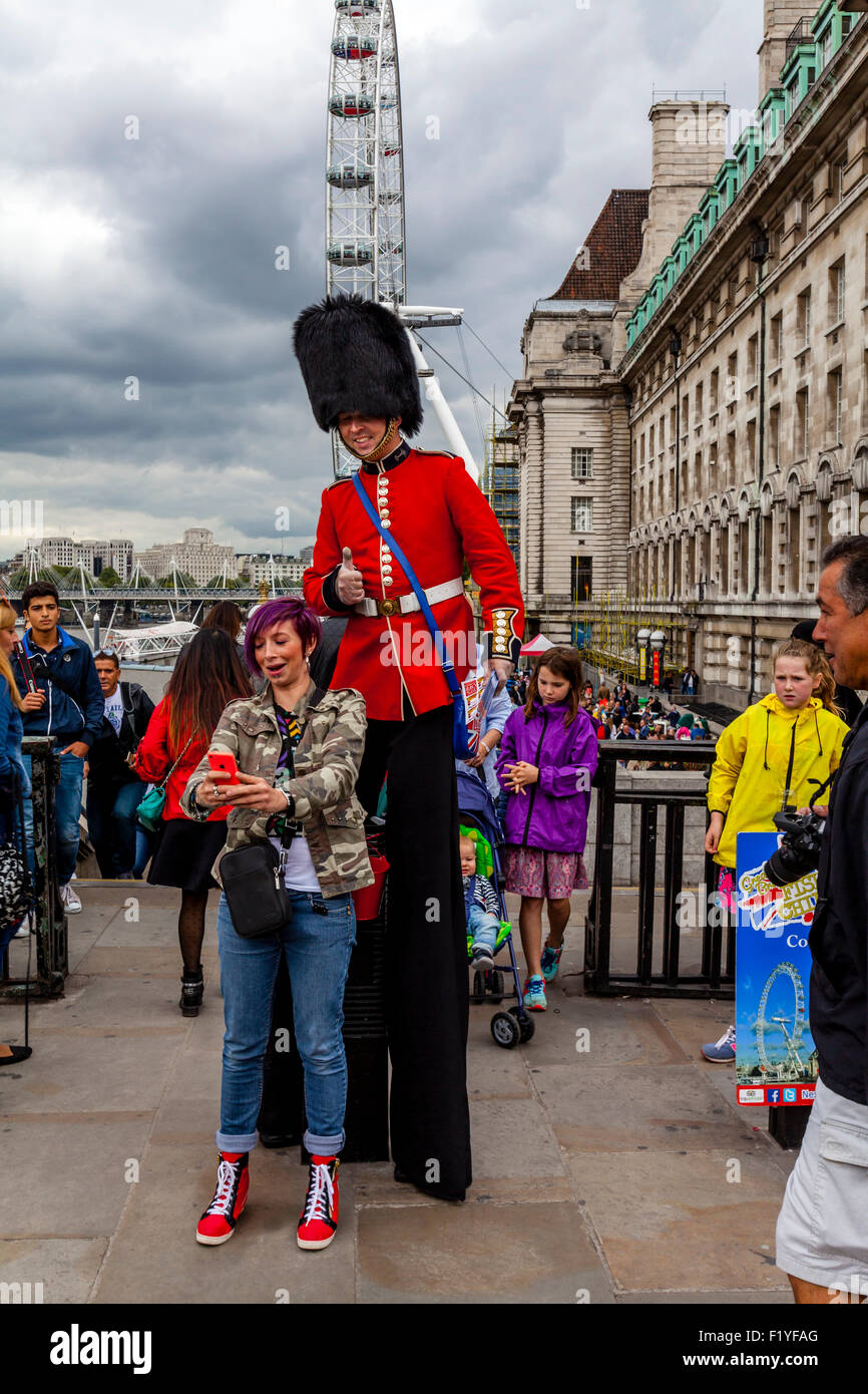 A Man Dressed In A Guards Uniform Hands Out Leaflets and Poses For Photographs With Tourists, London, England Stock Photo
