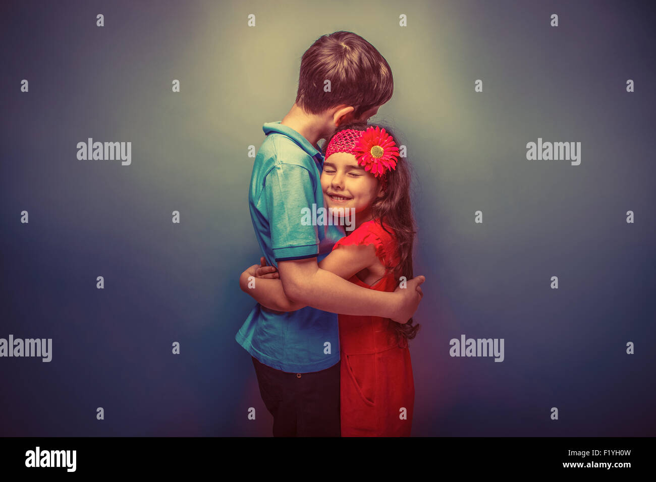 teen girl hugging a teenage  boy on gray  background retro Stock Photo