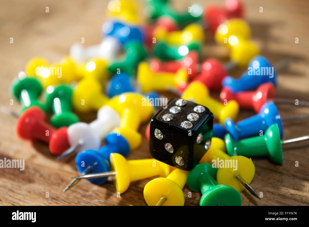 objects : die and colored pushpins on a table Stock Photo