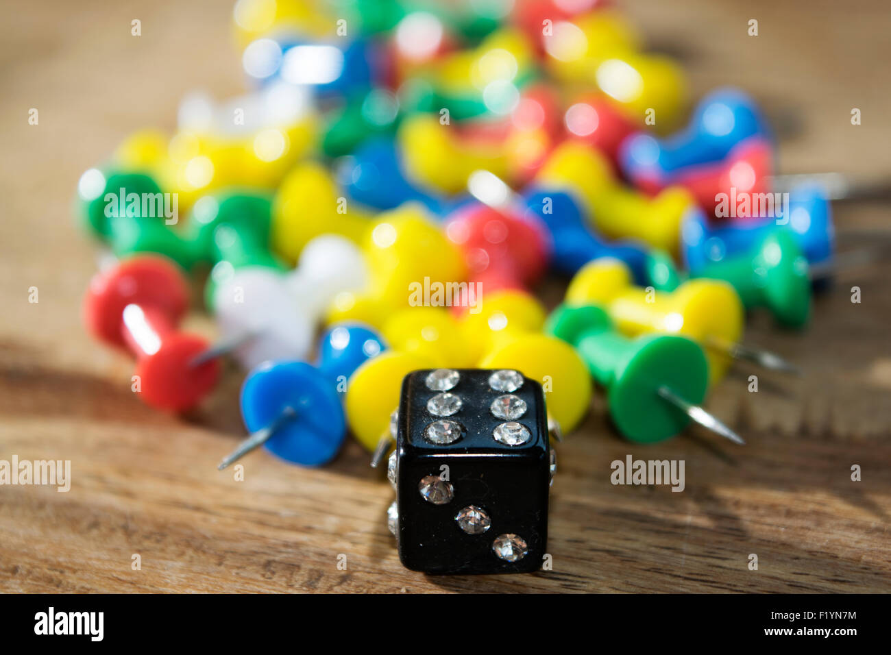 objects : die and colored pushpins on a table Stock Photo