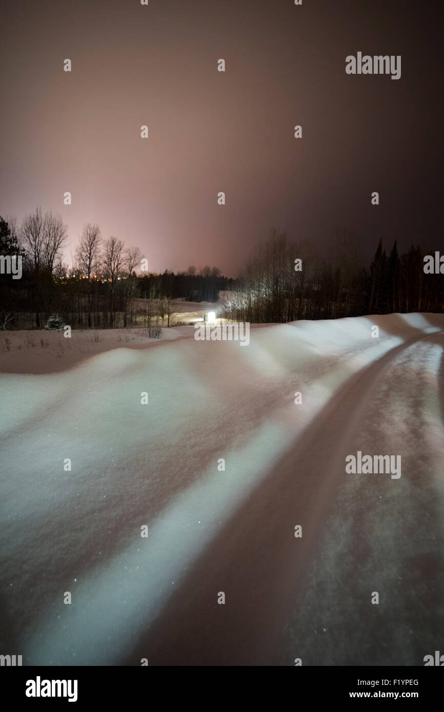 Pink glow in the night sky from city lights in winter with sparkling snow, Ely, MN, USA Stock Photo