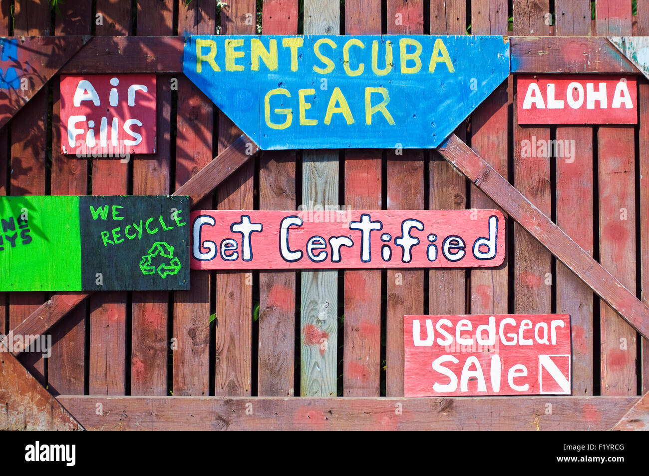 Signs advertising dives and diving gear on wooden fence in south Kona, Big Island, Hawaii Stock Photo