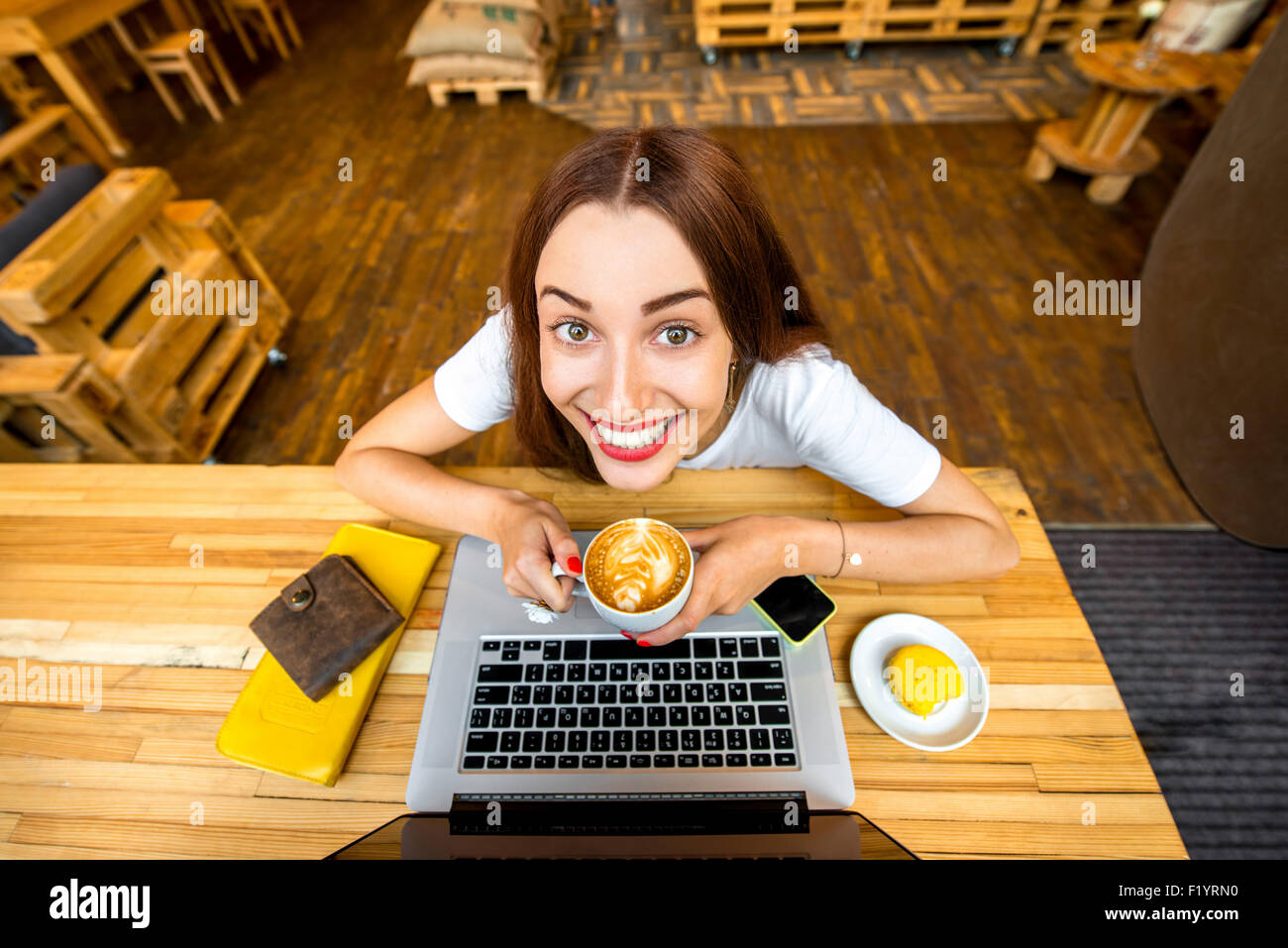 Woman enjoying cappuccino sitting with laptop Stock Photo