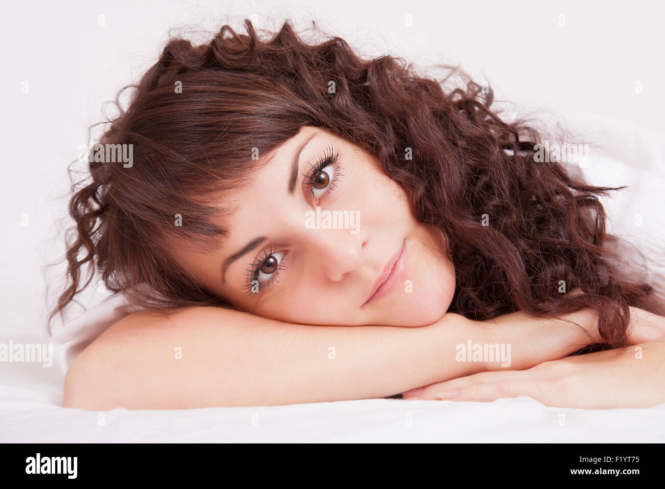 Beautiful young woman in white shirt lying on a bed Stock Photo - Alamy
