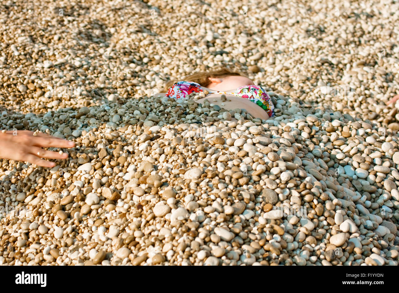 Girl covered with gravel on the beach Stock Photo Alamy